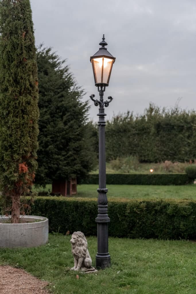 Gartenlaterne mit Löwenstatue im grünen Umfeld