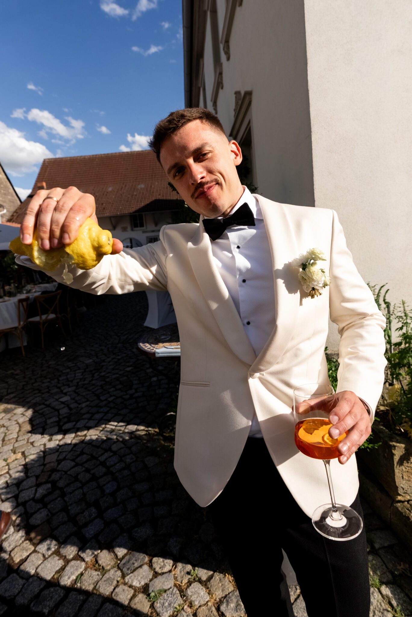 Bräutigam presst Zitrone in Cocktail im Innenhof