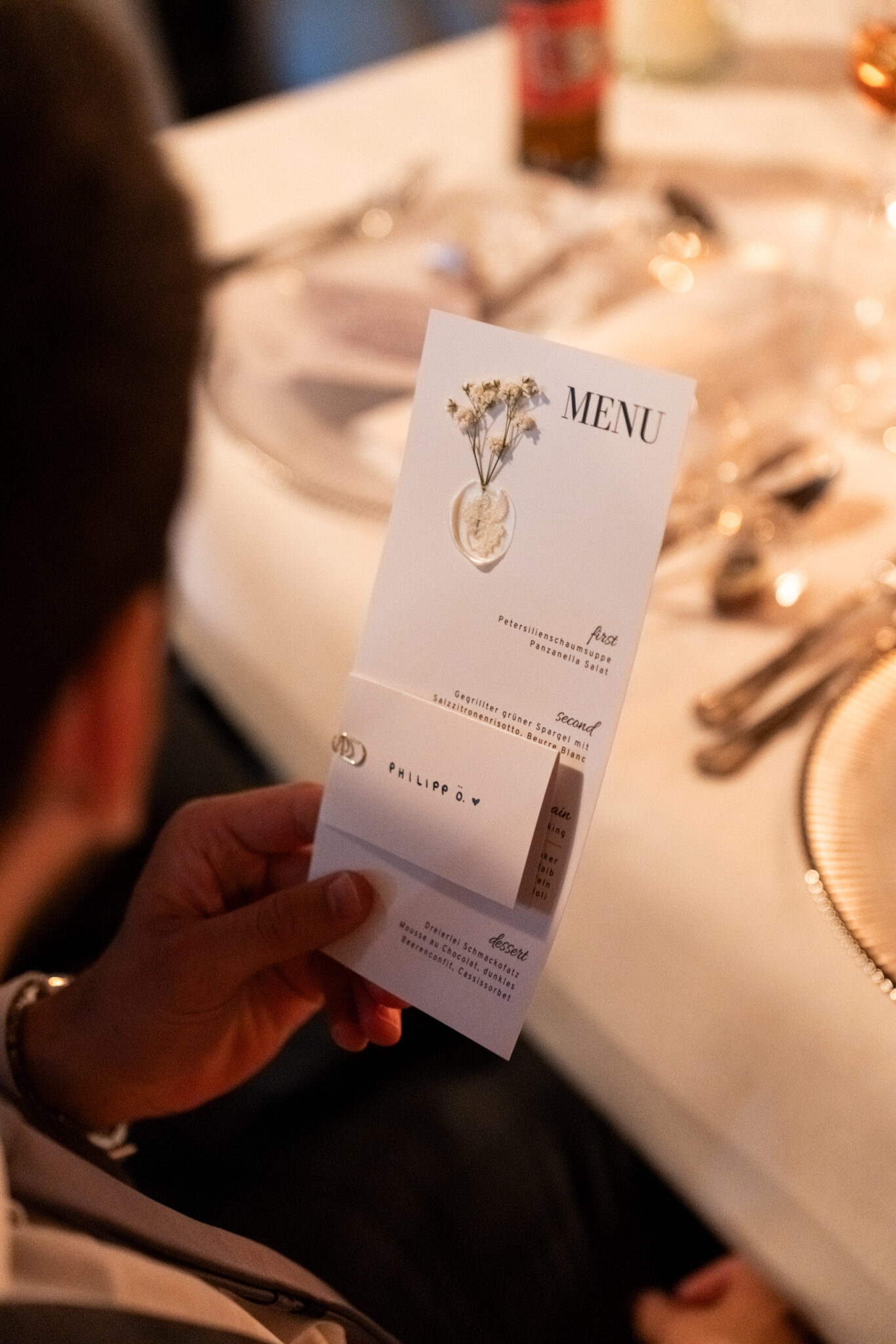 Gast hält Hochzeitsmenü am festlich gedeckten Tisch