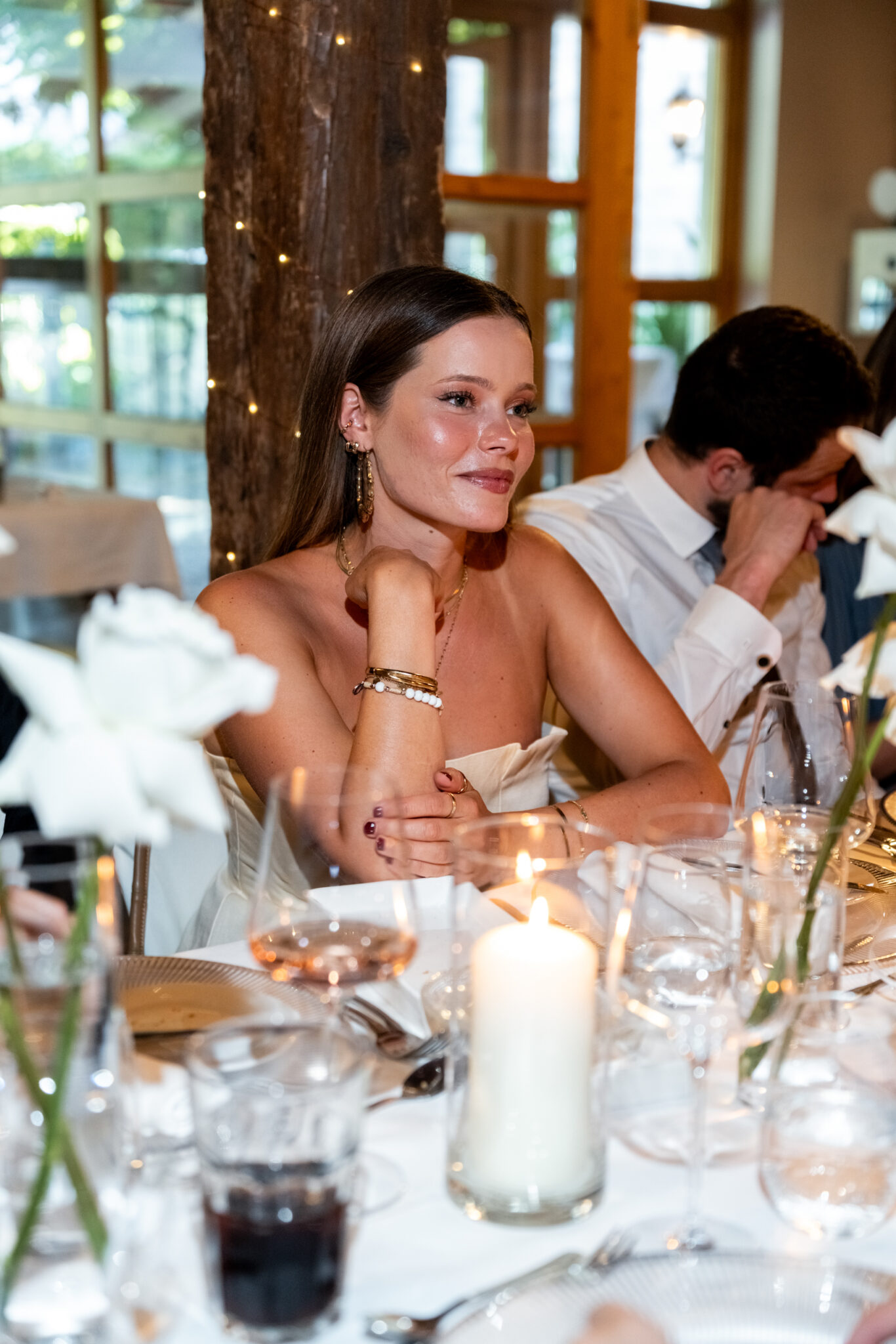 Hochzeitsgäste beim Dinner mit Kerzen und weißen Rosen