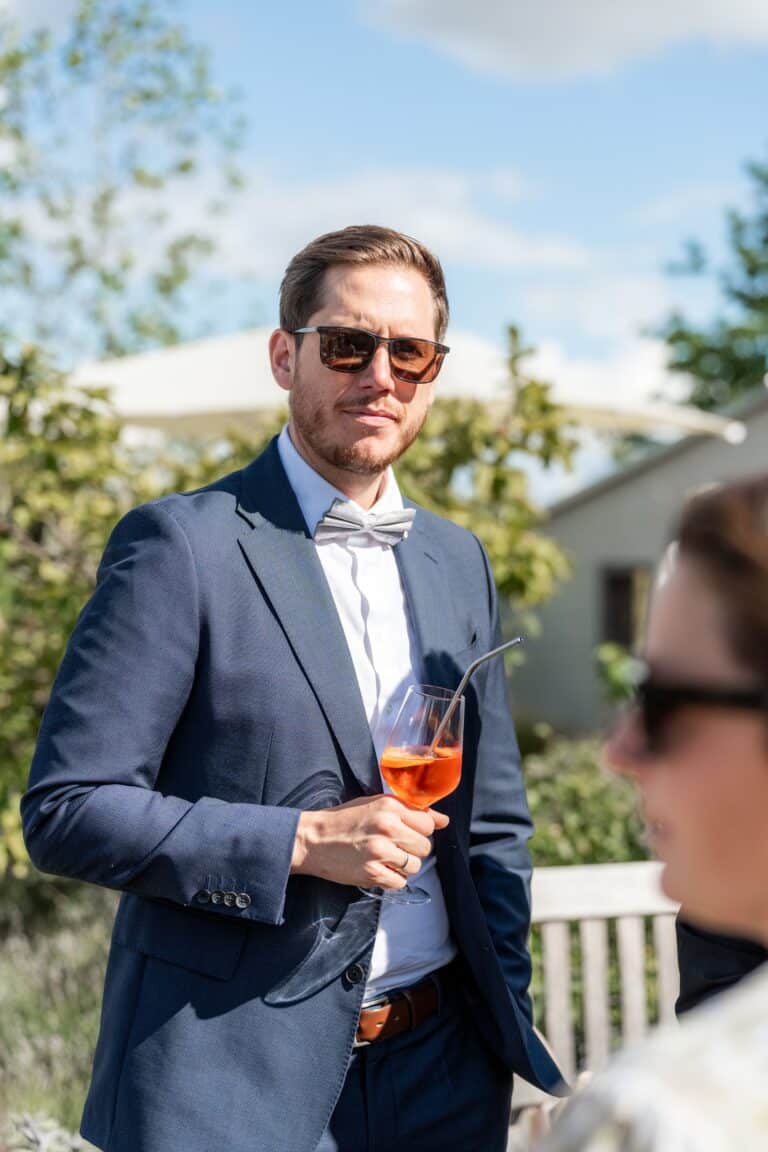 04580-florian-knusper-hochzeitsfotograf-wuerzburg-gast-mit-getraenk-garten-Villa Oriental