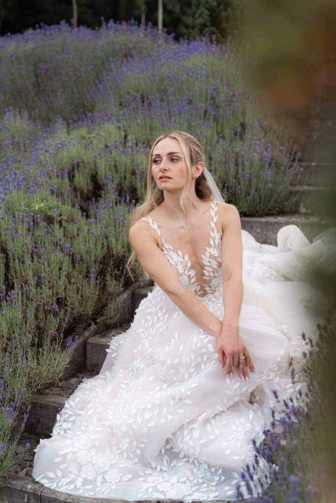 Braut im weißen Kleid sitzt im Lavendelgarten