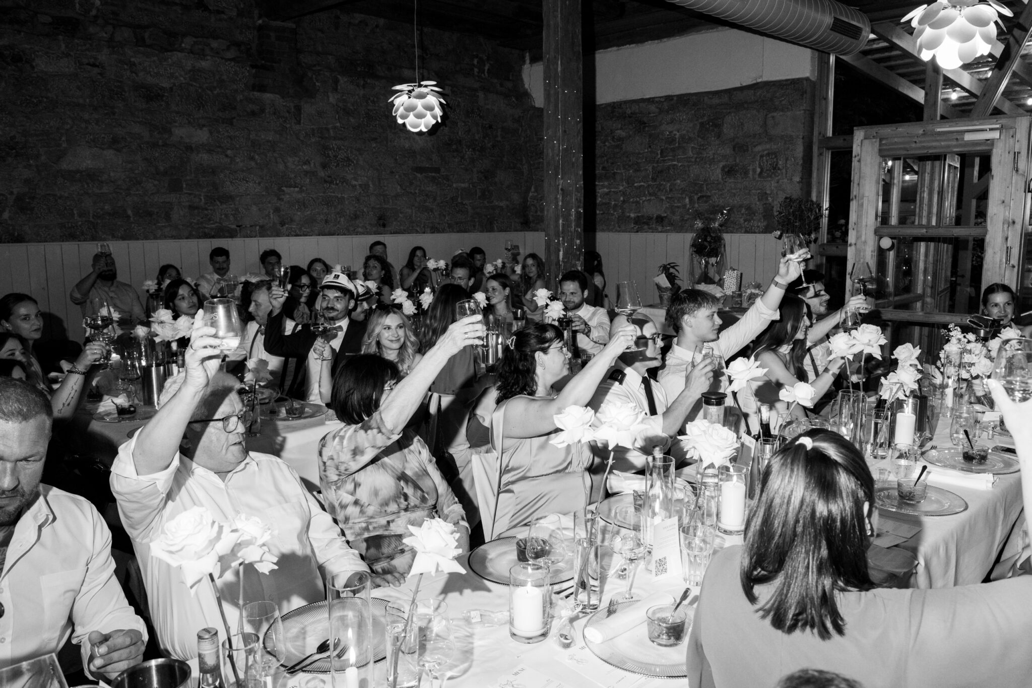 Hochzeitsgäste heben die Gläser beim Toast im Festsaal