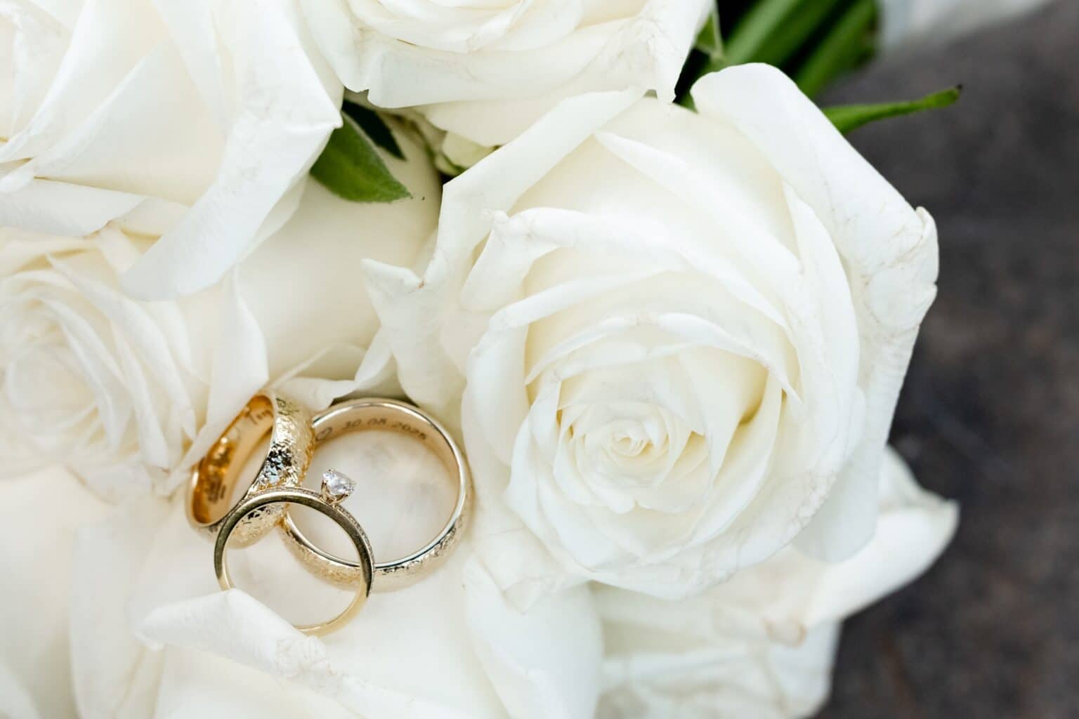 Goldene Trauringe auf weißen Rosen