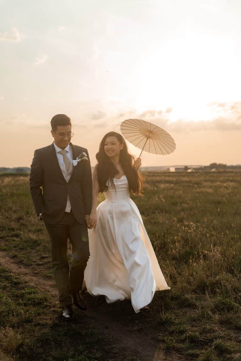 06146-florian-knusper-hochzeitsfotograf-wuerzburg-paar-mit-schirm-im-feld-Hotel Schindlerhof Nuernberg