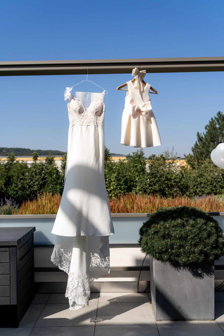 Brautkleid und Kinderkleid auf Terrasse im Freien hängen