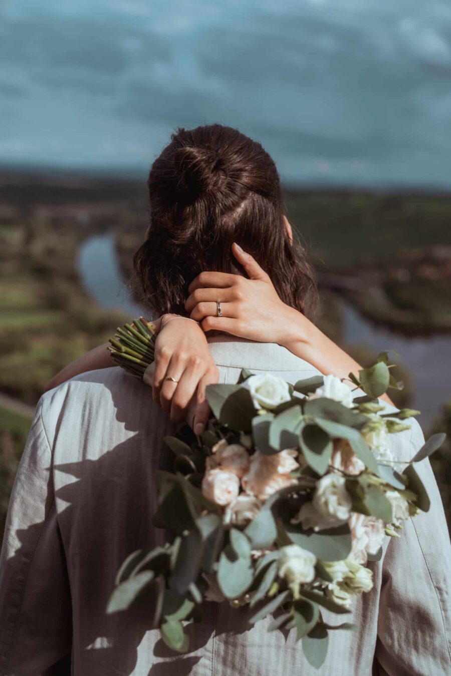 Hochzeitsumarmung mit Blumenstrauß im Freien