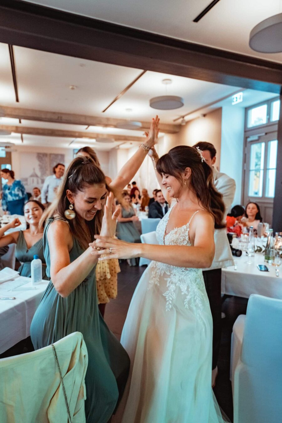 Braut tanzt mit Gästen im Festsaal.