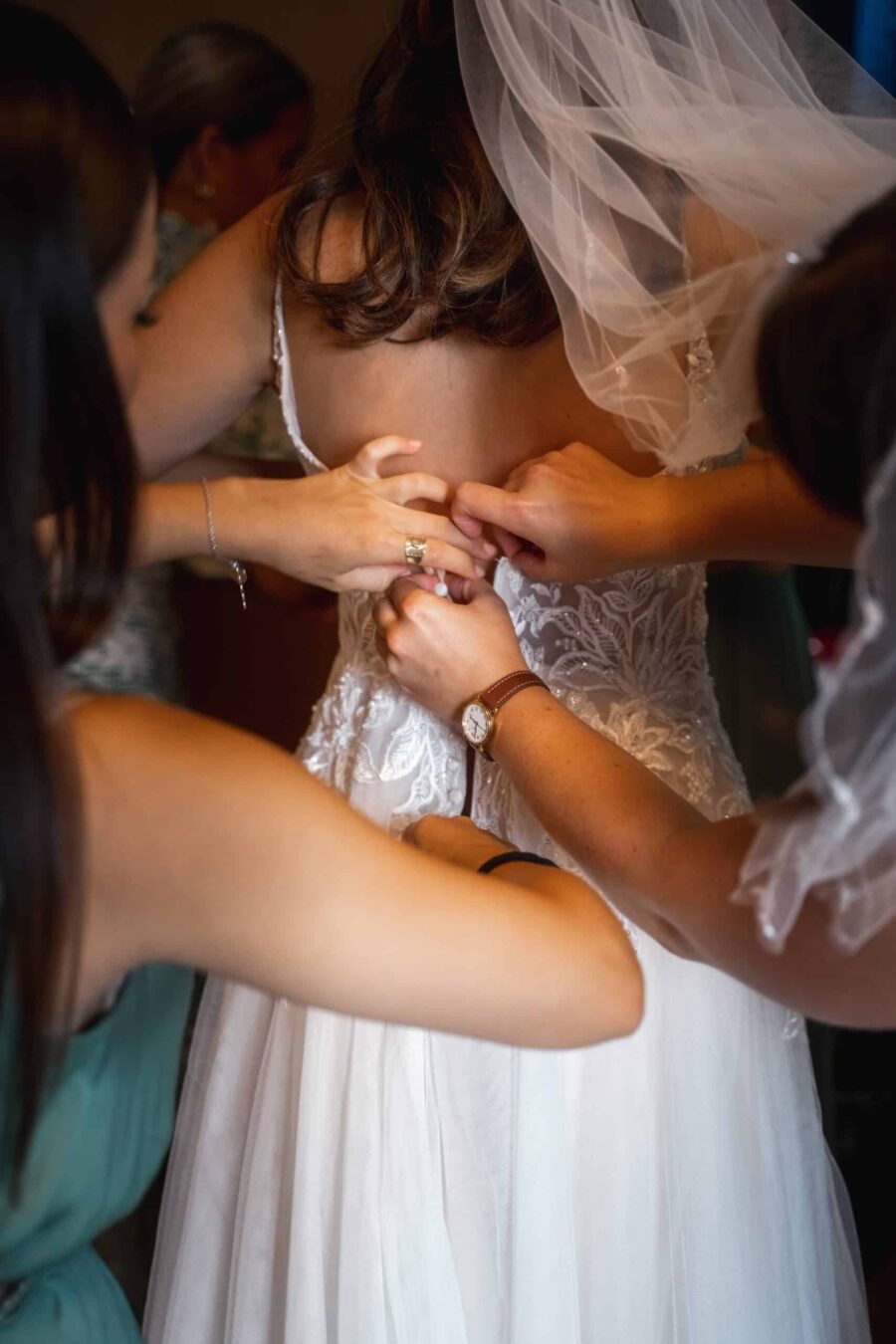 Brautkleid wird von Helferinnen zugeschnürt