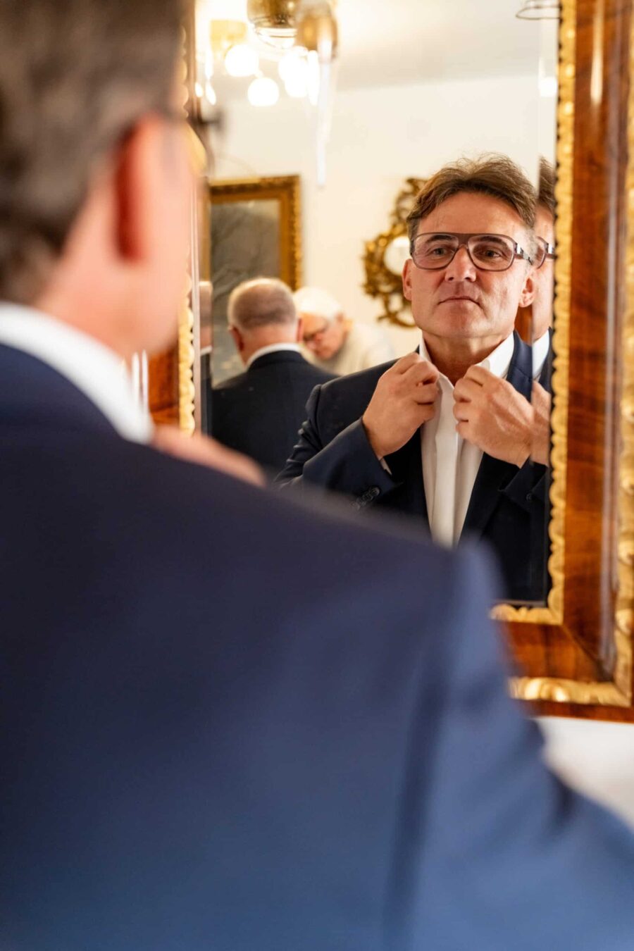 Mann im Anzug richtet Krawatte vor Spiegel