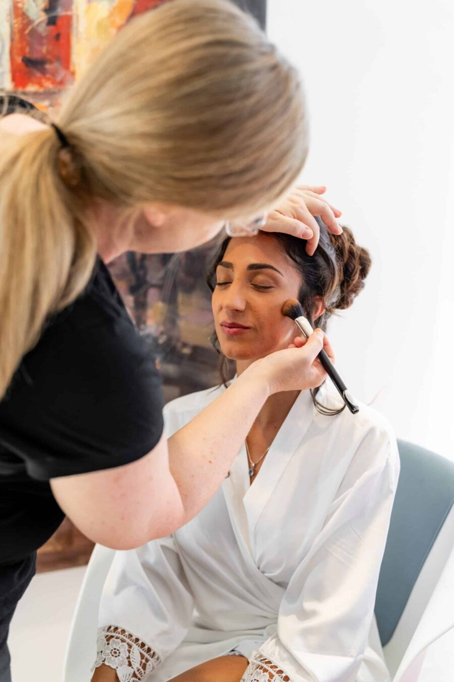 Braut beim Schminken am Hochzeitstag.
