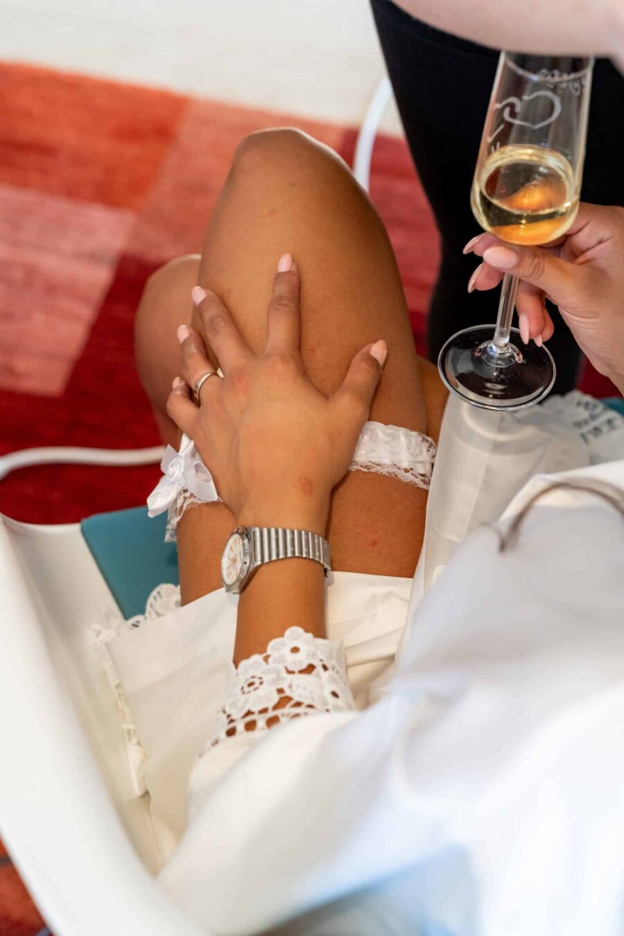 Braut beim Anlegen des Strumpfbandes mit Sektglas