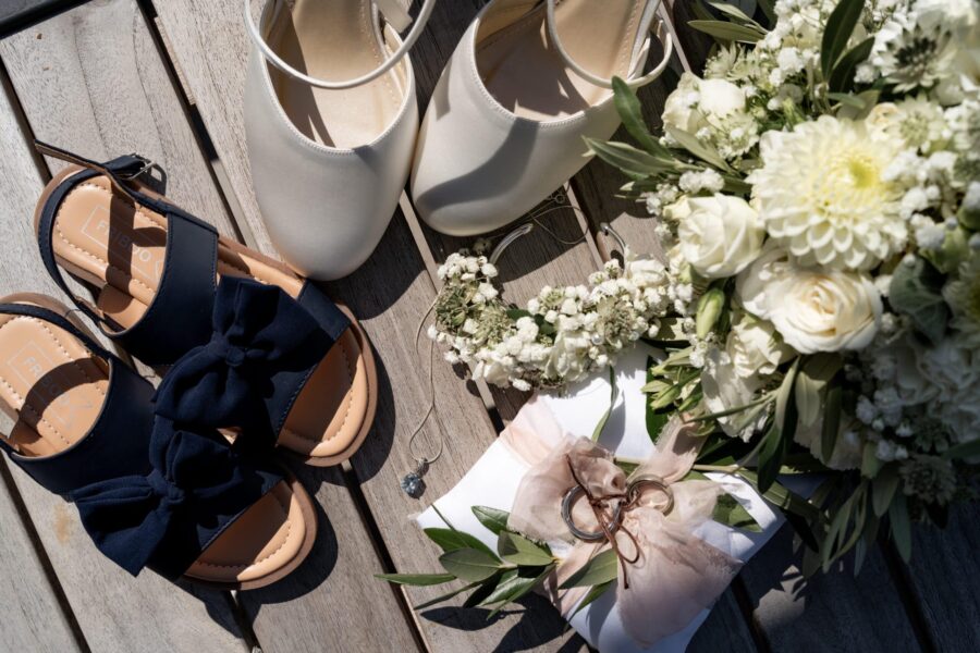 Brautschuhe und Blumenstrauß auf Holztisch.