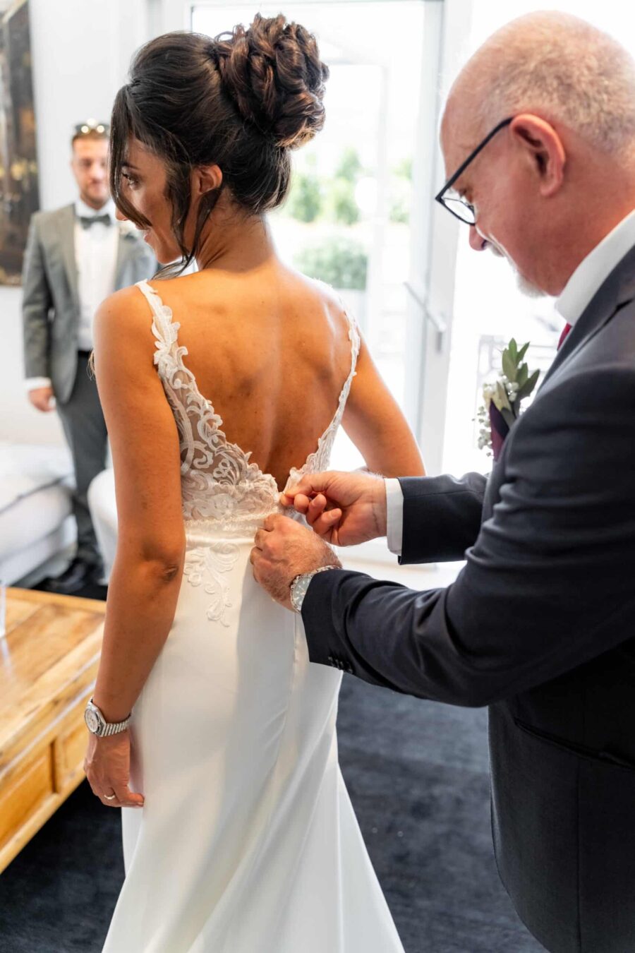 Brautkleid wird von Begleiter geschlossen