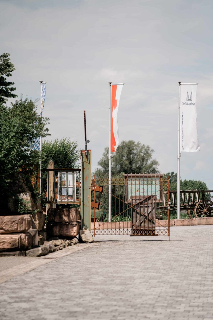 Eingangstor mit Fahnen und Pflanzen im Freien.