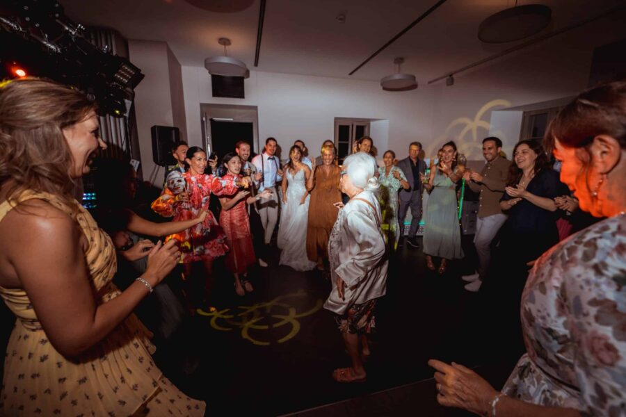 Hochzeitstanz mit fröhlichen Gästen im Festsaal.