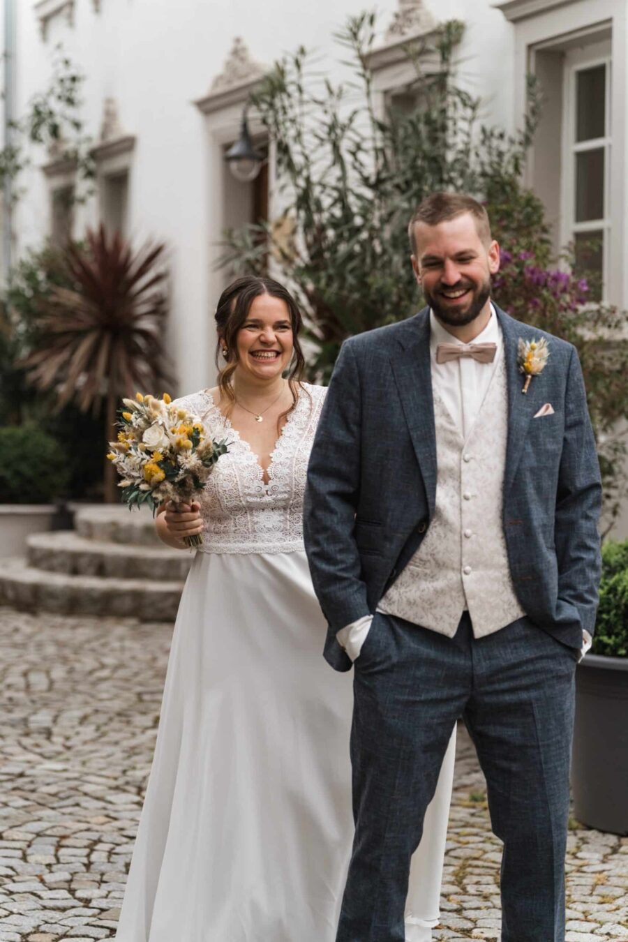 Brautpaar lächelt in eleganter Hochzeitskleidung draußen