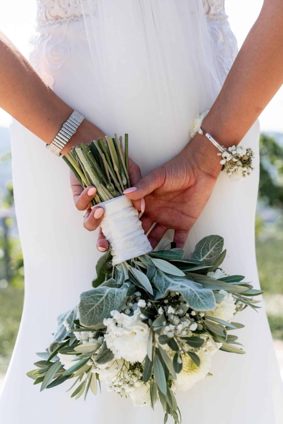 Braut hält Blumenstrauß elegant in weißen Kleid