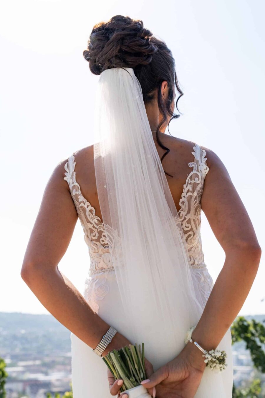 Braut im weißen Kleid mit Schleier im Freien.