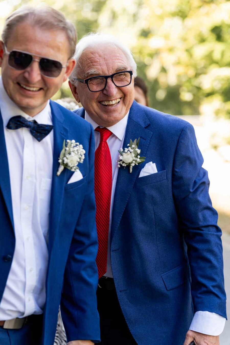 Gäste in eleganter Kleidung im Garten feiern