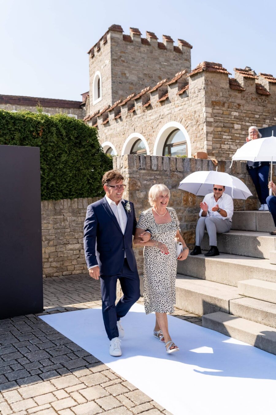 Hochzeitspaar geht vor historischer Steinmauer