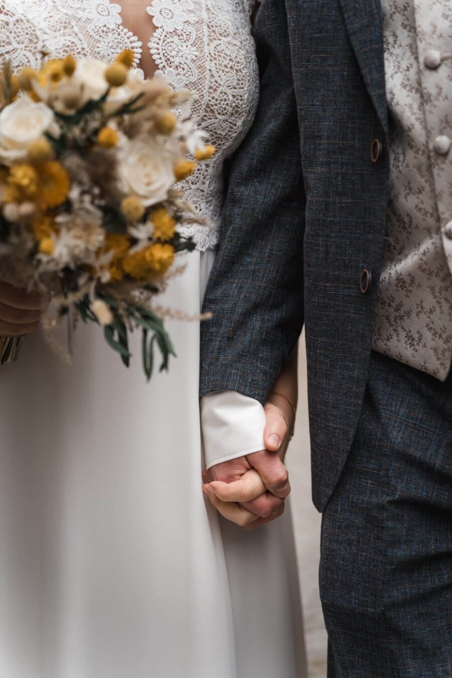 Brautpaar hält Hände mit Blumenstrauß