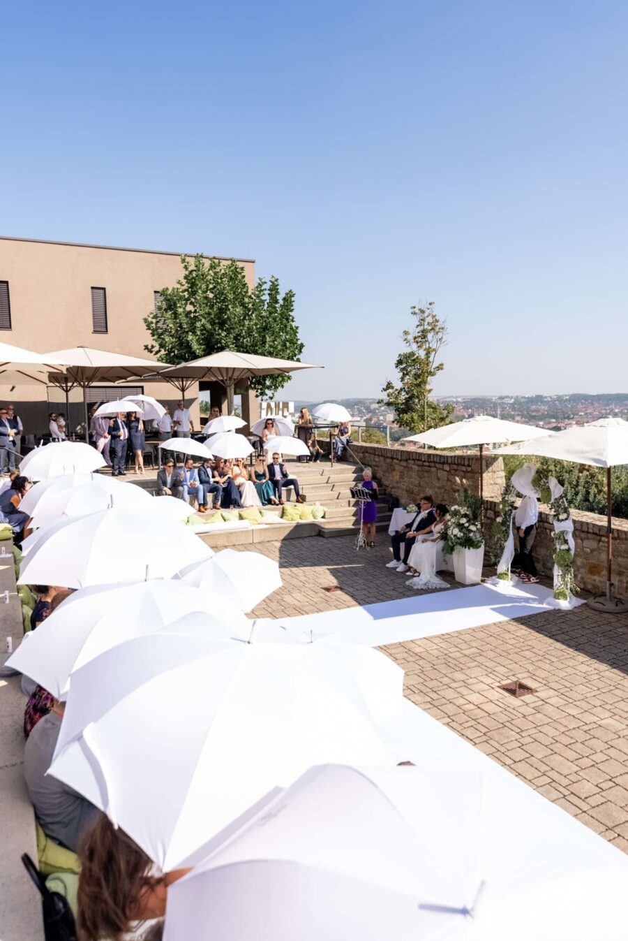 Hochzeitsgäste mit Sonnenschirmen im Freien