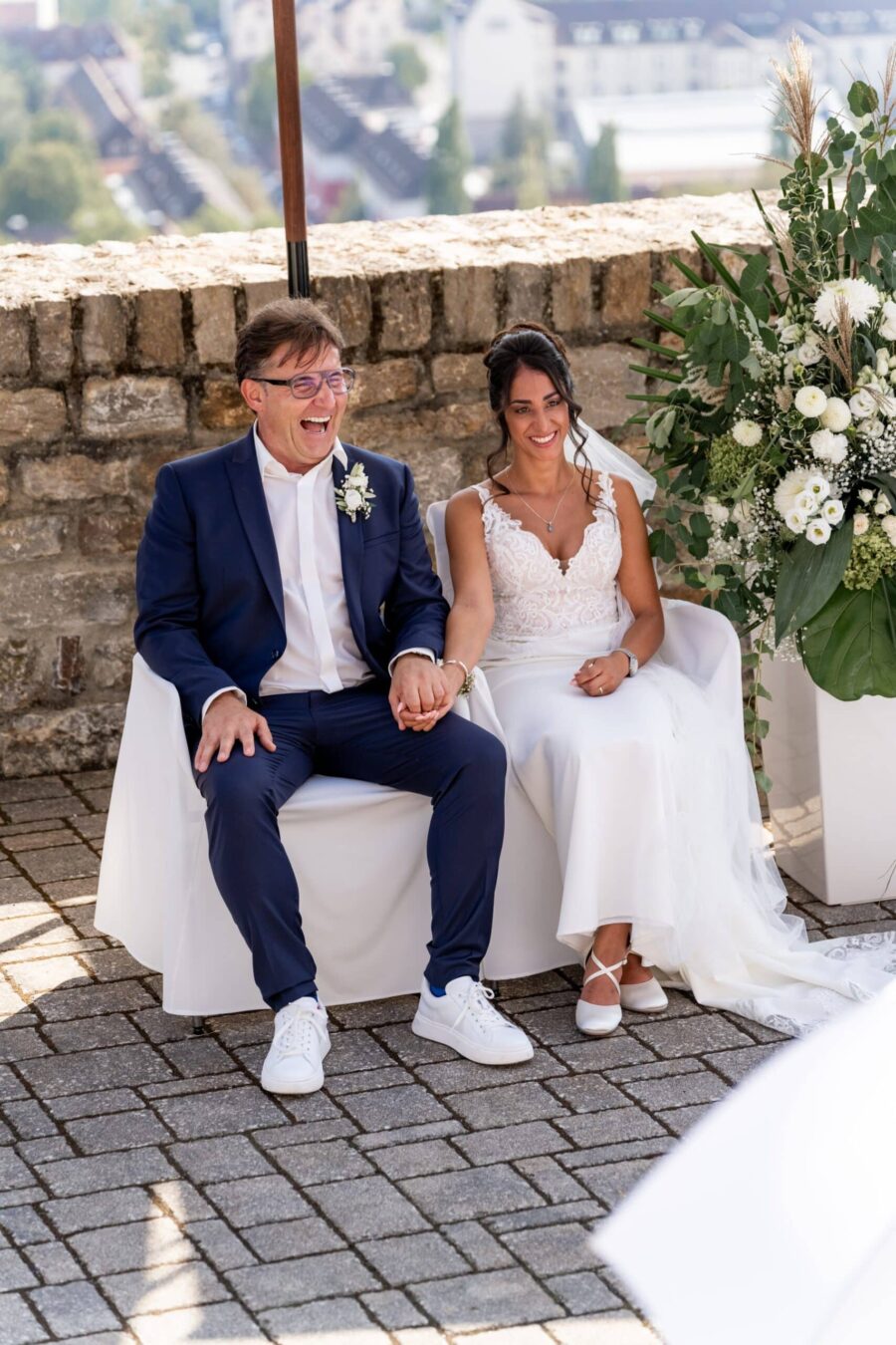 Brautpaar auf Terrasse mit Blumendekoration.