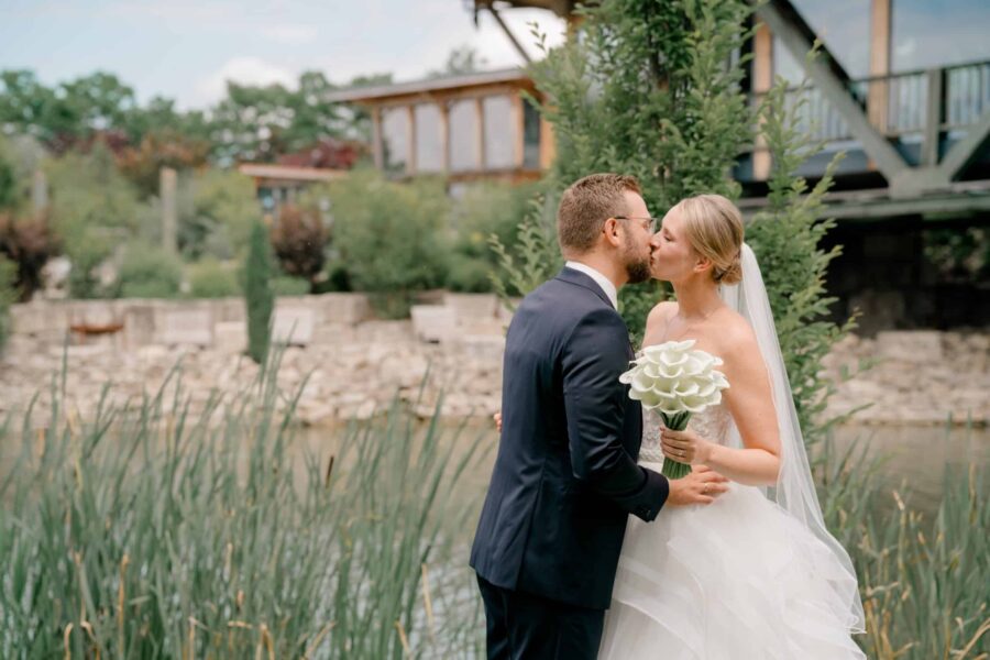 Brautpaar küsst sich vor Landschaftsgarten