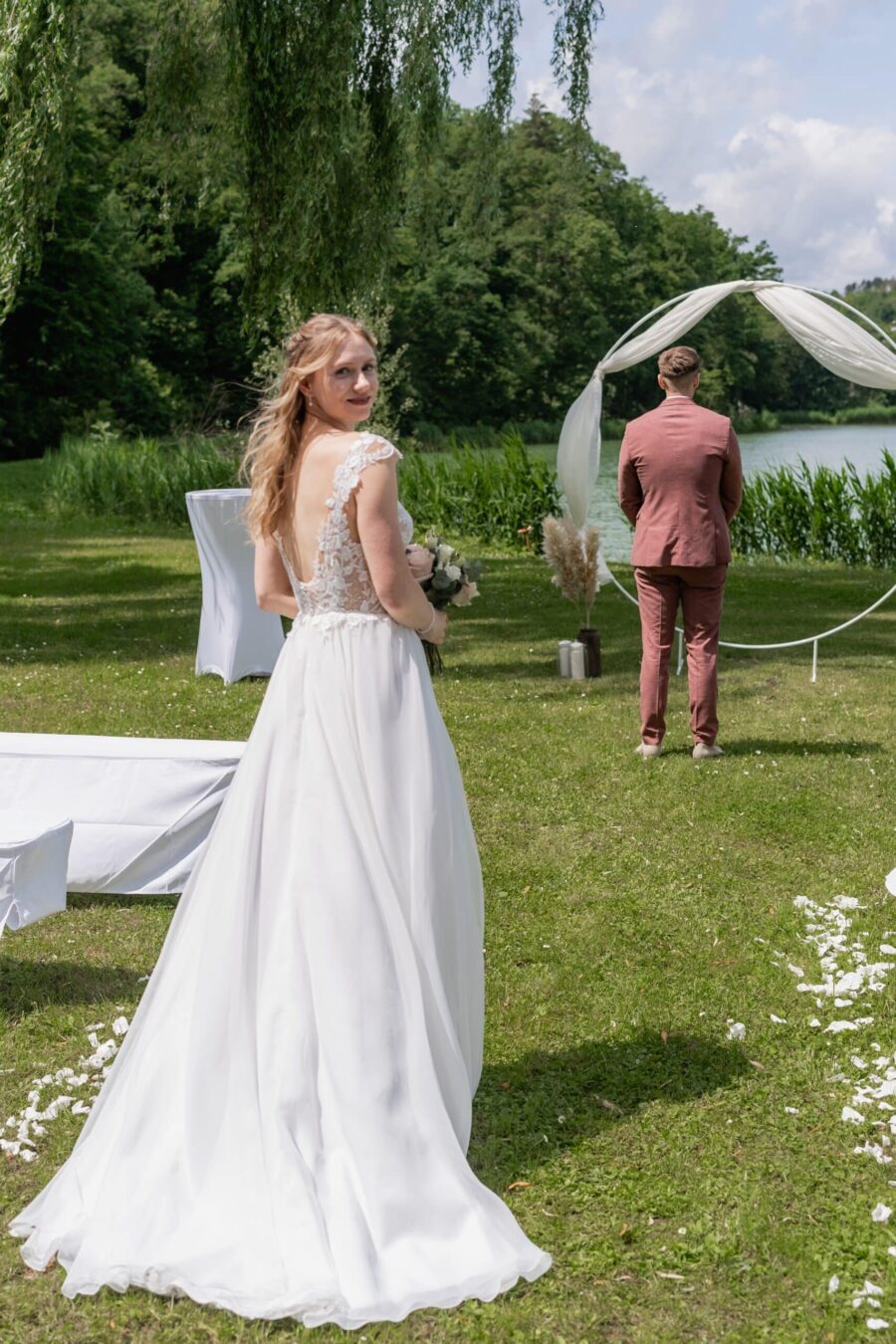Brautpaar vor Hochzeitsbogen am See im Grünen