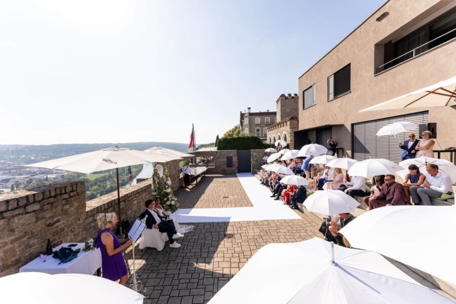 Hochzeit auf Burgterrasse mit Gästen und Regenschirmen