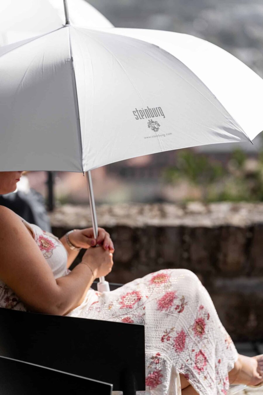 Sitzende Hochzeitsgast mit Sonnenschirm im Garten