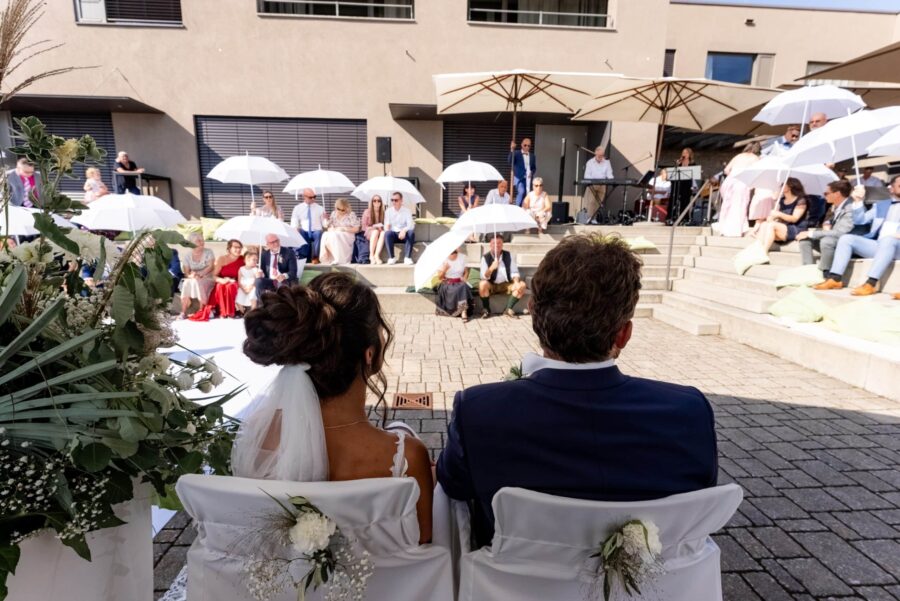 Brautpaar vor Hochzeitsgästen im Außenbereich