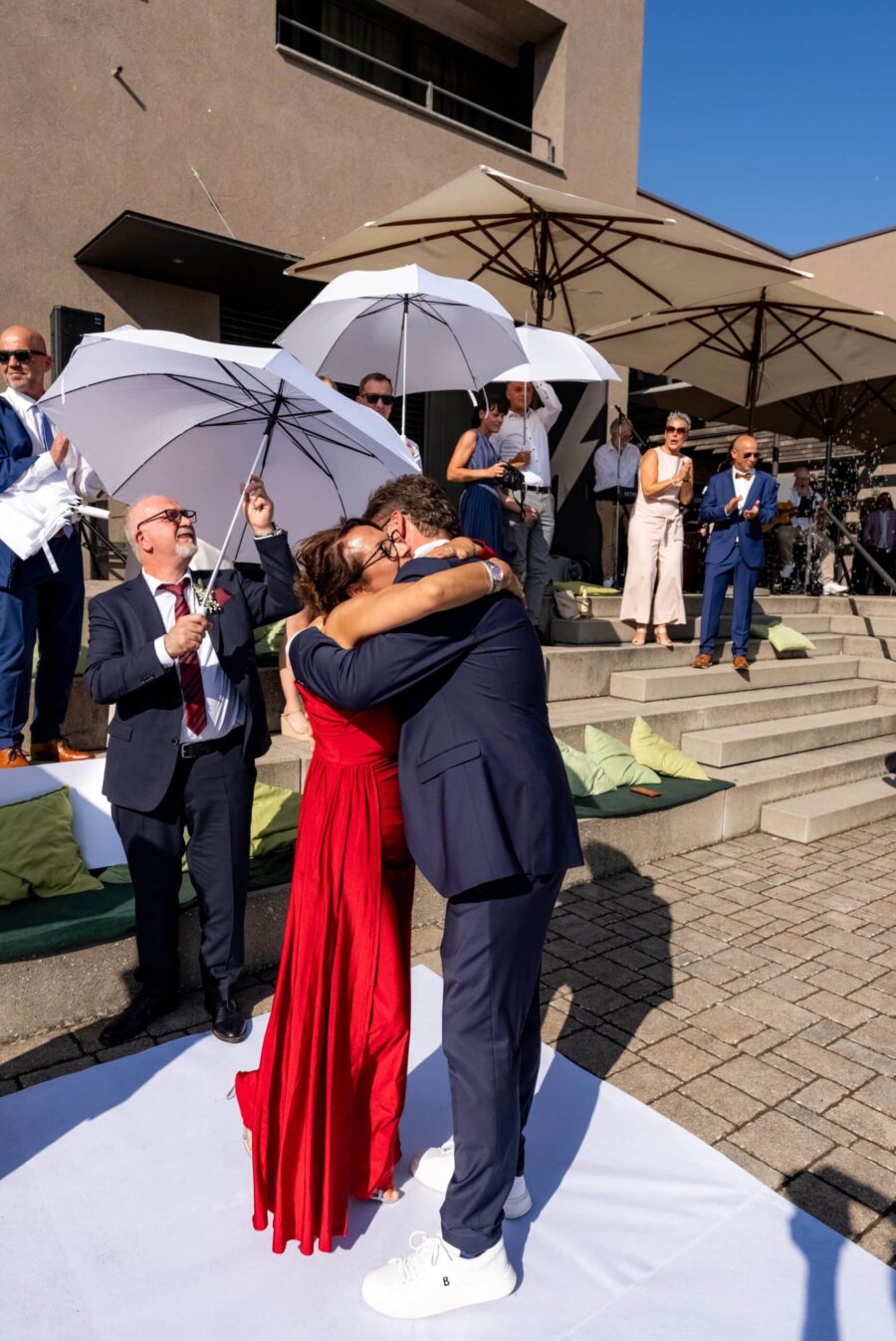 Hochzeitspaar umarmt sich unter Sonnenschirmen