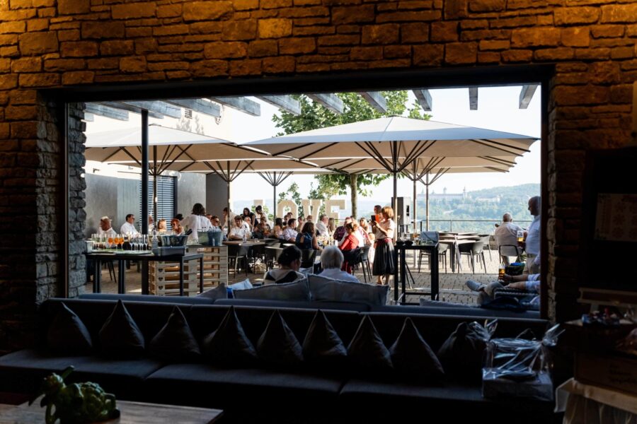 Hochzeitsfeier auf Terrasse mit Gästen und Sonnenschirmen.