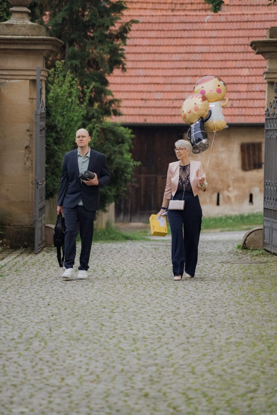 Gäste mit Luftballons auf Kopfsteinpflasterweg