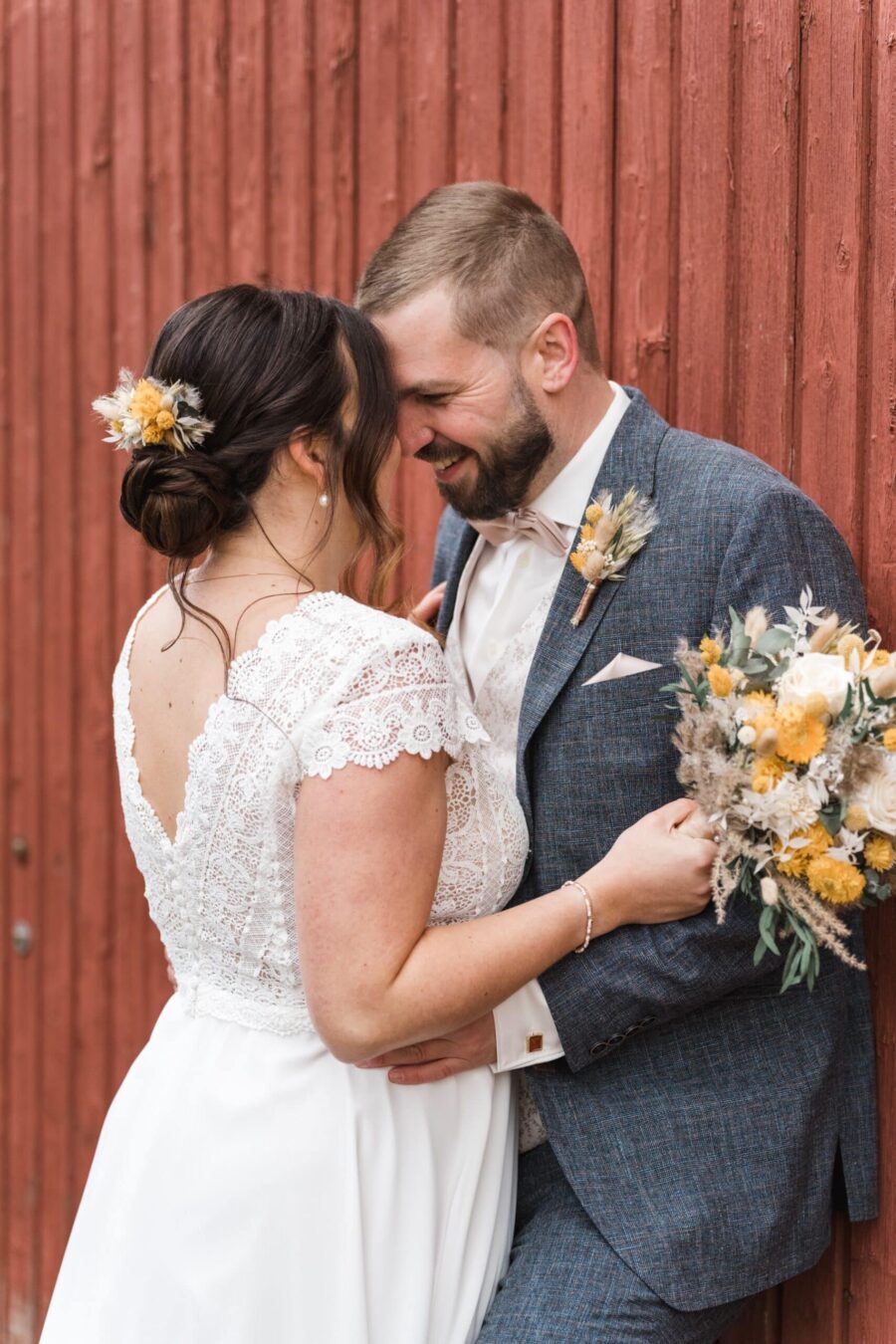 Brautpaar lächelt vor roter Holzwand