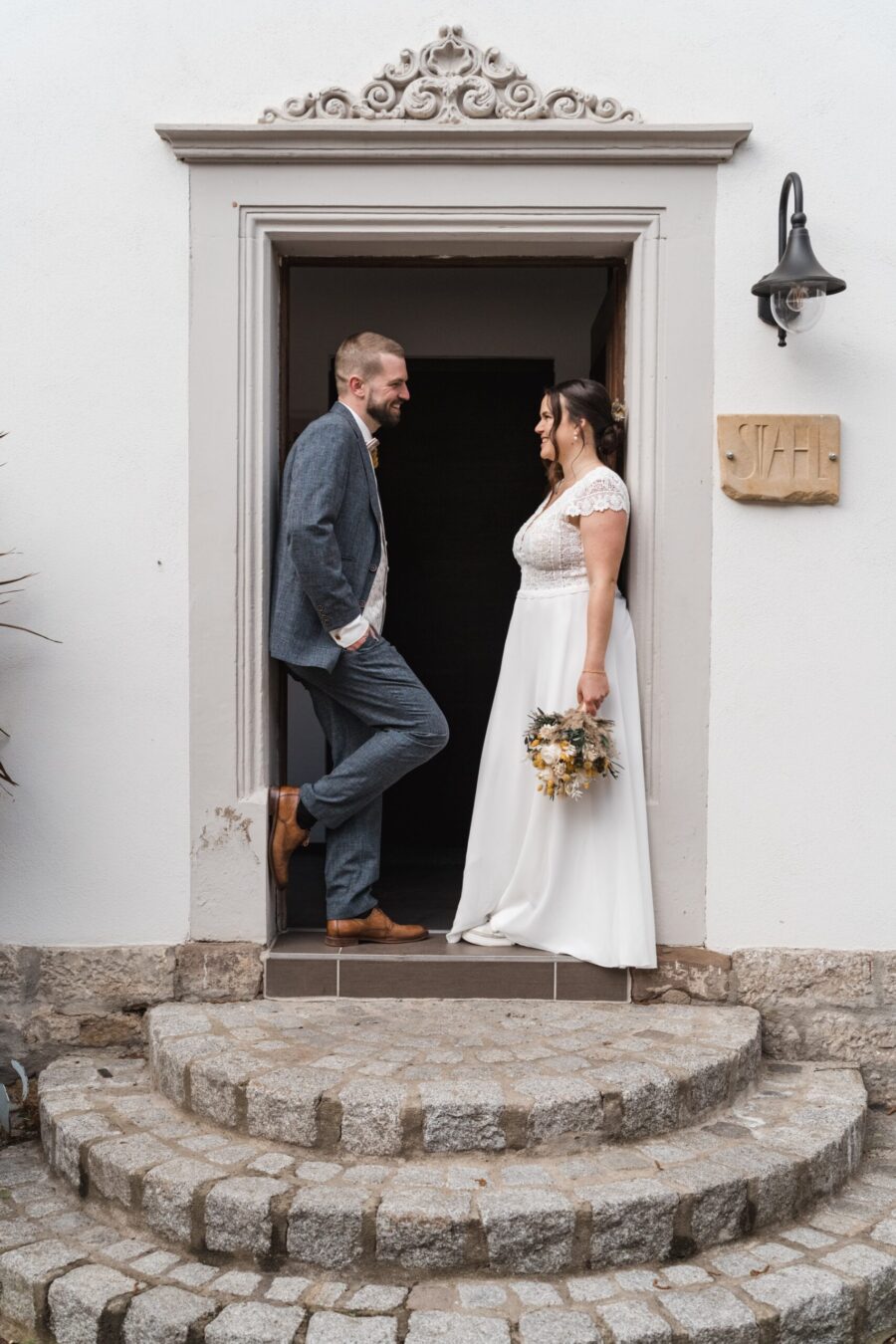 Brautpaar lächelt sich an vor Türöffnung.