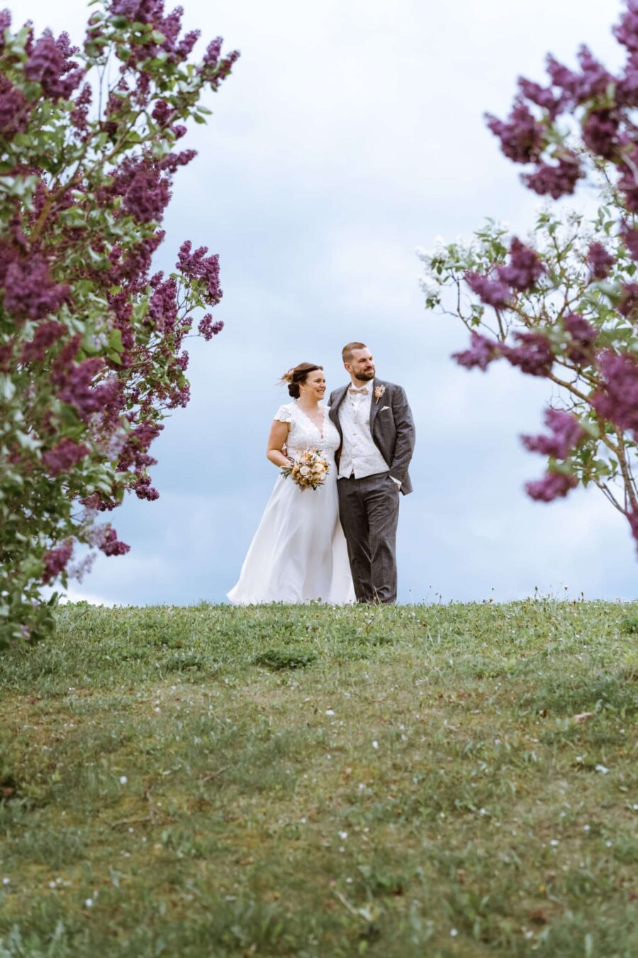 Brautpaar im Frühling mit blühenden Fliederbüschen