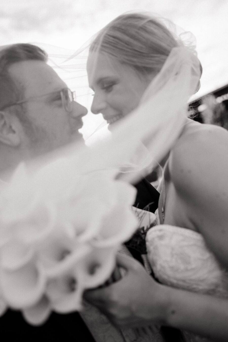 Brautpaar lächelt sich unter Brautschleier an