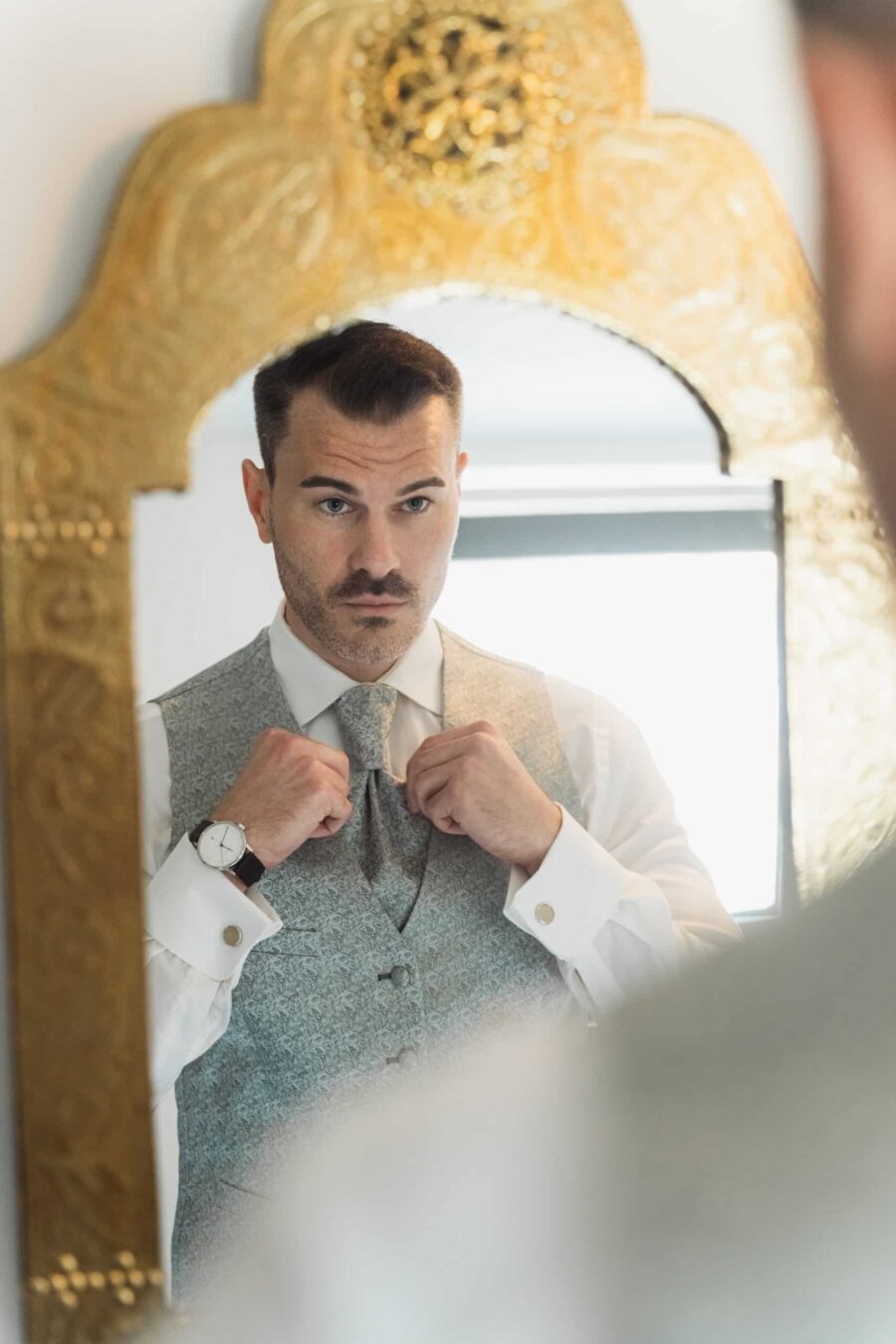 Bräutigam richtet Krawatte vor Spiegel