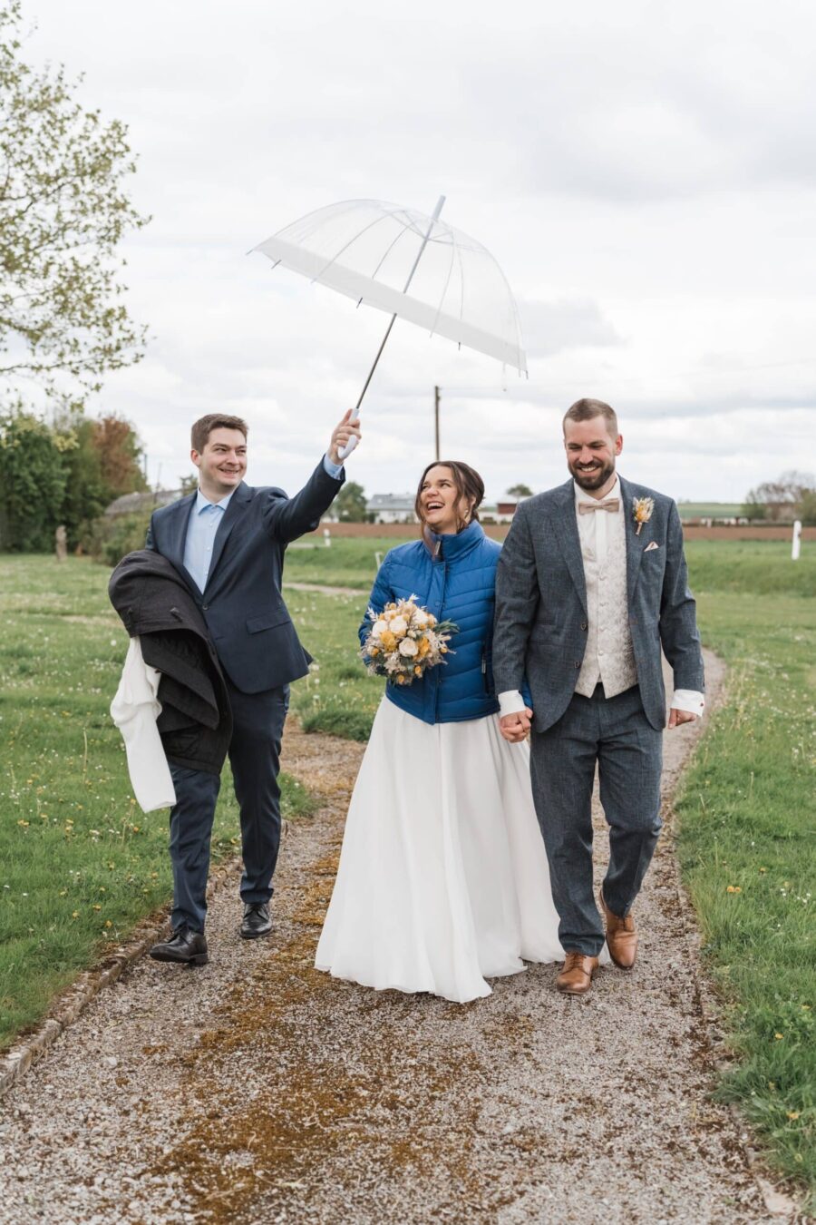 Brautpaar spaziert mit Regenschirm im Freien