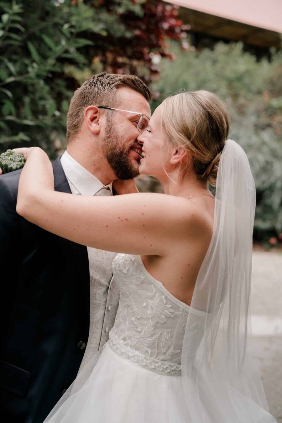 Brautpaar küsst sich im Garten.