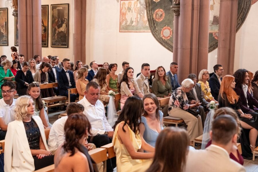 Hochzeitsgäste sitzen in einer Kirche.