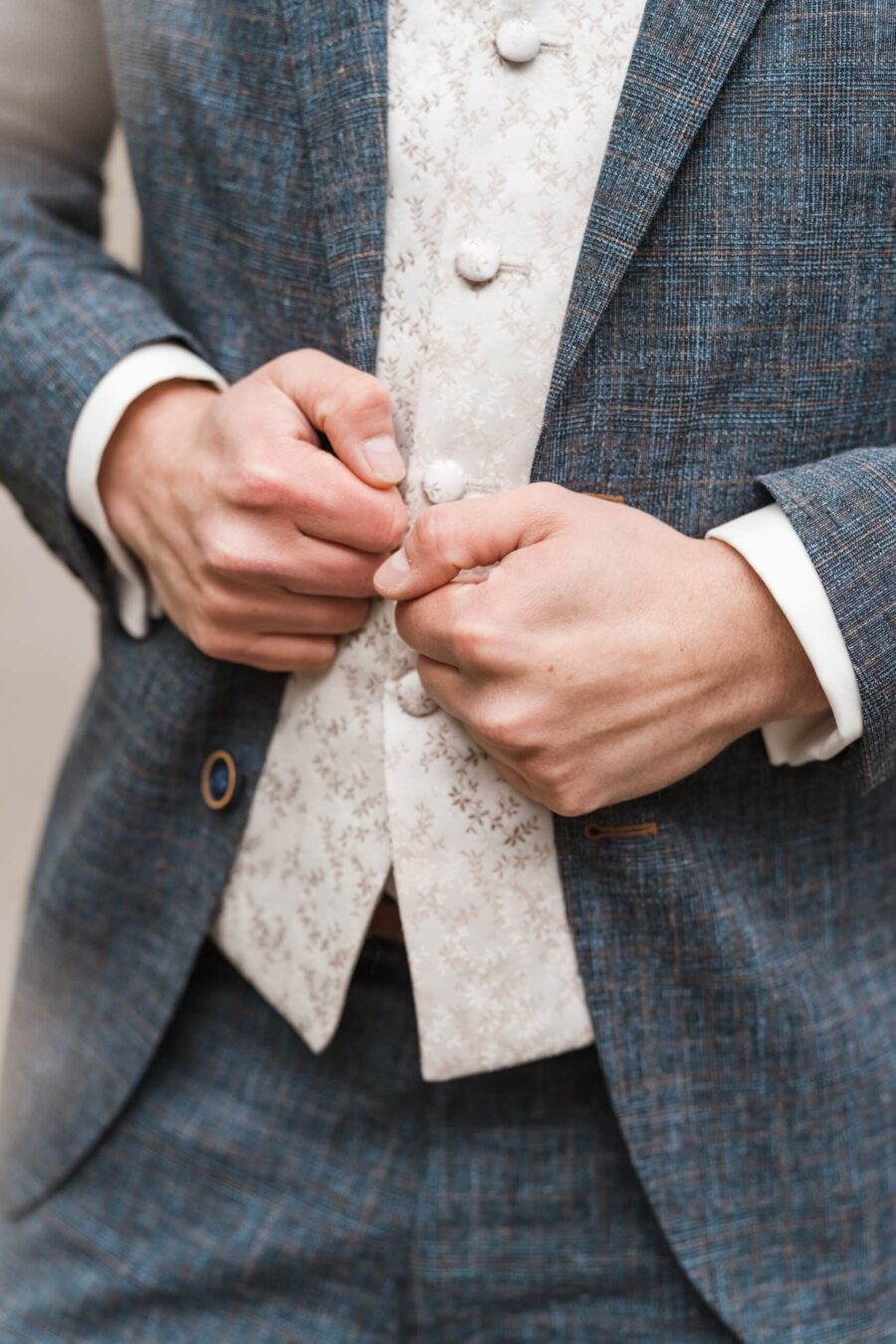 Eleganter Bräutigam im Anzug justiert Weste.