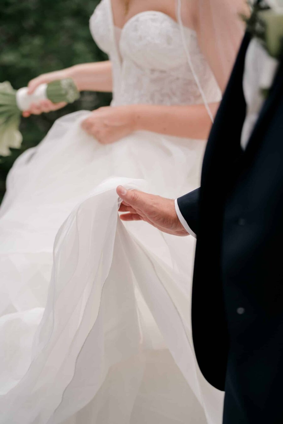 Brautpaar hält Brautkleid im Garten