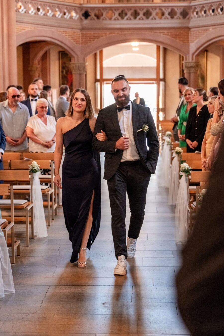 Hochzeitsgäste schreiten durch dekorierte Kirche.