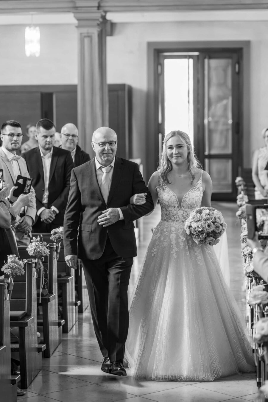 Braut schreitet mit Begleitung zum Altar