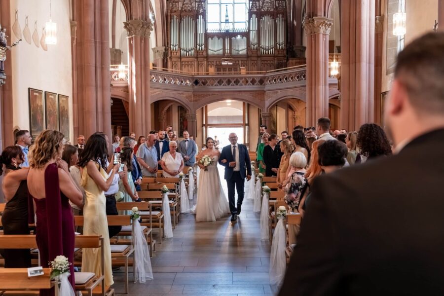 Braut mit Begleitung schreitet zum Altar in der Kirche