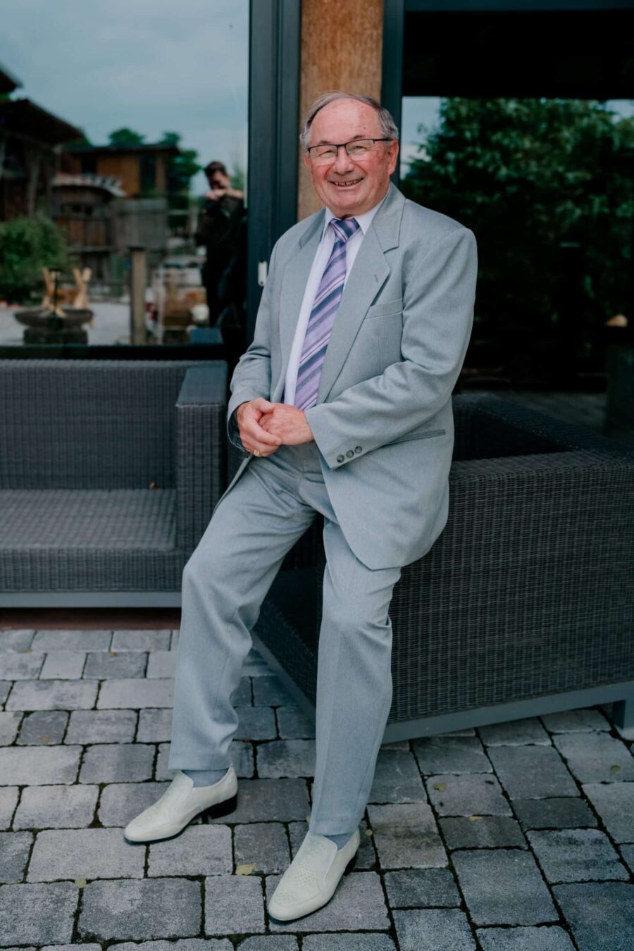 Älterer Herr im Anzug auf Terrasse bei Hochzeit.
